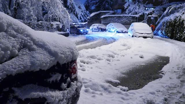 在大雪过后的夜晚，汽车行驶在积雪覆盖的街道上视频素材