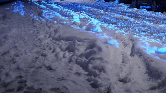 在大雪过后的夜晚，汽车行驶在积雪覆盖的街道上视频素材