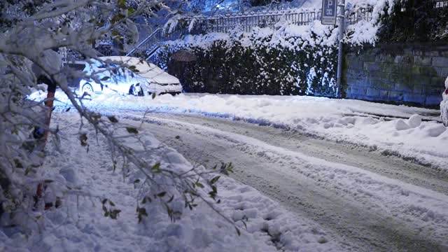 在大雪过后的夜晚，汽车行驶在积雪覆盖的街道上视频素材