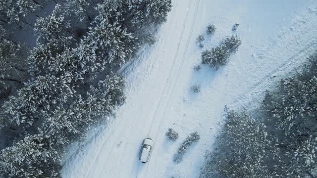 无人机鸟瞰图，越野车在冰雪路面上行驶，在冬季探索当地景观视频素材