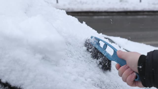 一场大雪过后，司机把车上的积雪清理干净。视频素材