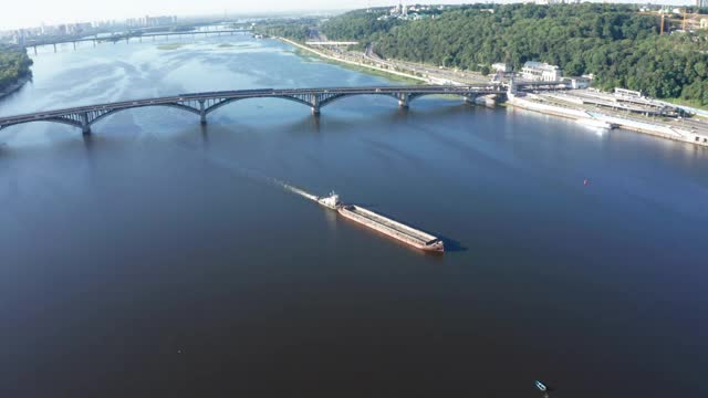 内河驳船在拖着漂浮物沿河道行驶，无人机在空中轨道拍摄视频素材