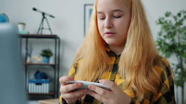 情绪化的女孩享受视频游戏与智能手机触摸屏在家里的乐趣视频素材