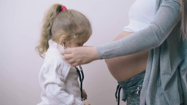 女孩在家把听诊器放在孕妇肚子上视频素材