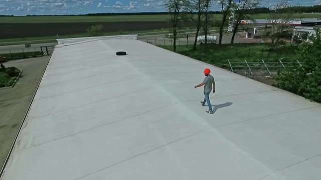技术专家在建筑物的平屋顶上行走。屋顶上戴着橙色安全帽的男工人正在制定建设太阳能农场的计划。视频素材画面2