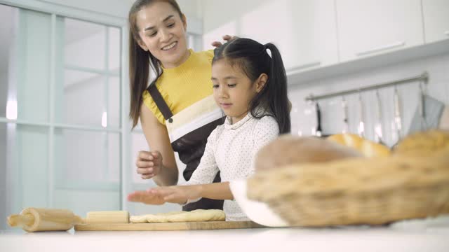 在厨房里，妈妈教小女儿如何用面团做饼干或蛋糕视频素材