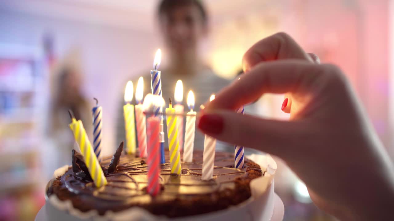 女性手闪电蜡烛的特写生日蛋糕。一个面目全非的白种女人正在为派对准备美味的甜点。聚会和幸福视频素材