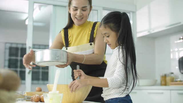 妈妈和女儿在厨房里做面团做饼干或蛋糕视频素材