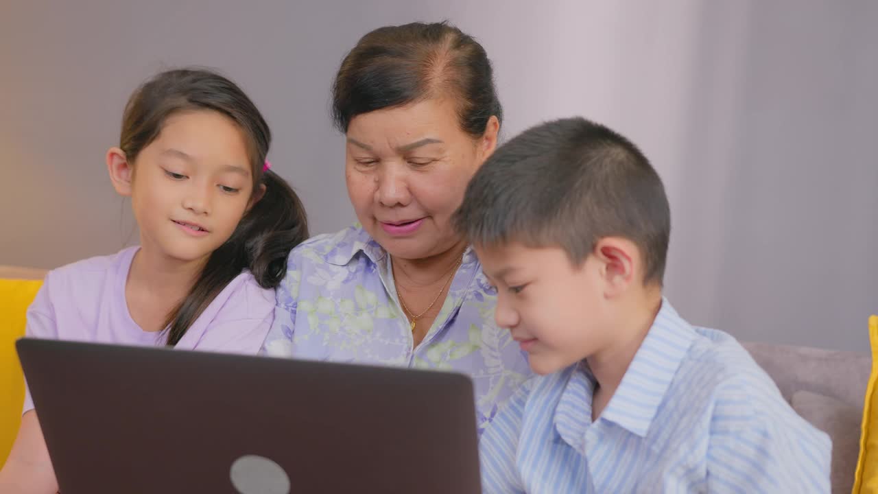 孙子在家里的客厅教祖母用笔记本电脑视频素材