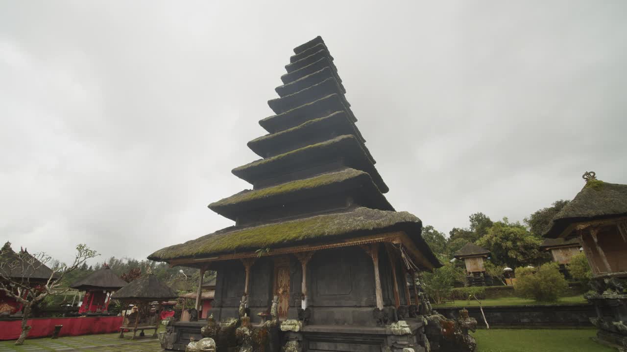 近距离拍摄在印尼巴厘岛的Besakih寺庙的宗教宝塔建筑周围，令人惊叹的宝塔覆盖在一个阴天的草视频素材