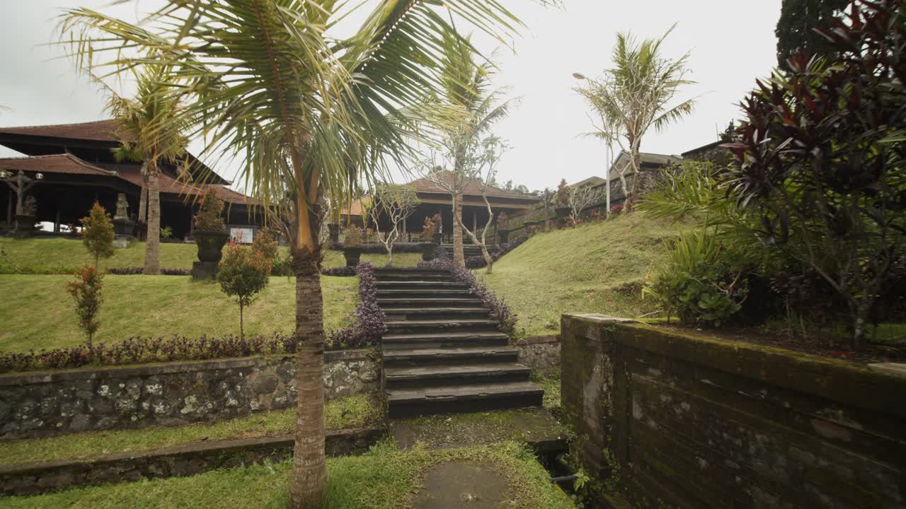 在巴厘岛的一座古老的黑石寺庙里走上楼梯的镜头美丽的寺庙地面上有古树和繁花视频素材