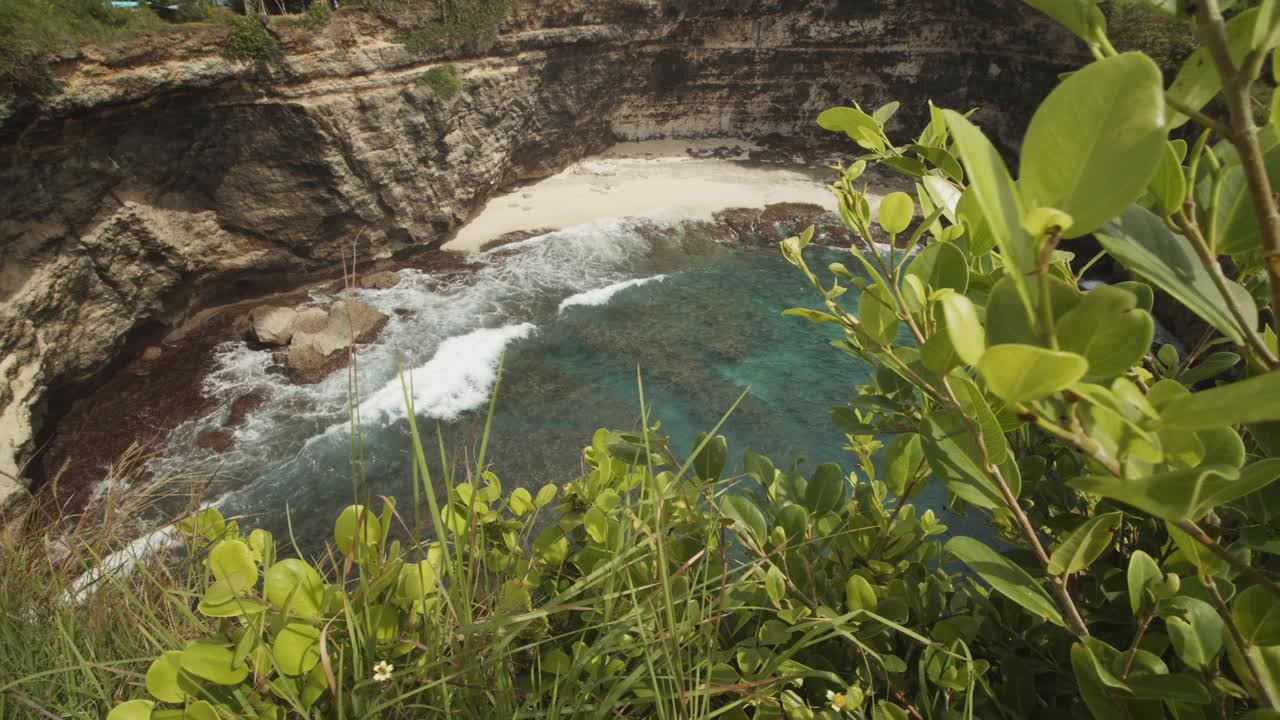 在印度尼西亚巴厘岛的破碎海滩Pasih Uug，海浪冲击着令人惊叹的蓝色沙滩和陡峭的海洋悬崖视频素材