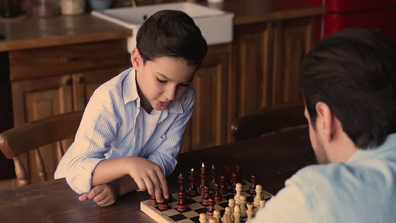 聪明专注的小男孩和爸爸下棋。视频素材