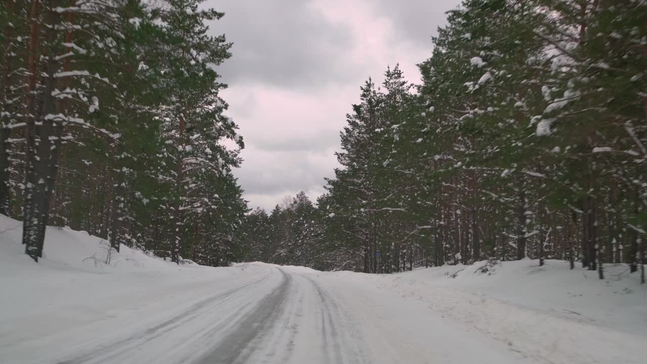 在森林里覆盖着雪的湿滑道路上小心驾驶。冬天，汽车在空旷的小路上行驶。视频素材