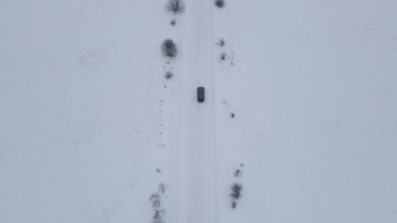 无人机俯视图的汽车车辆行驶在雪道景观在冬天，鸟瞰汽车汽车行驶在乡村道路上。冬季危险的旅行状况视频素材