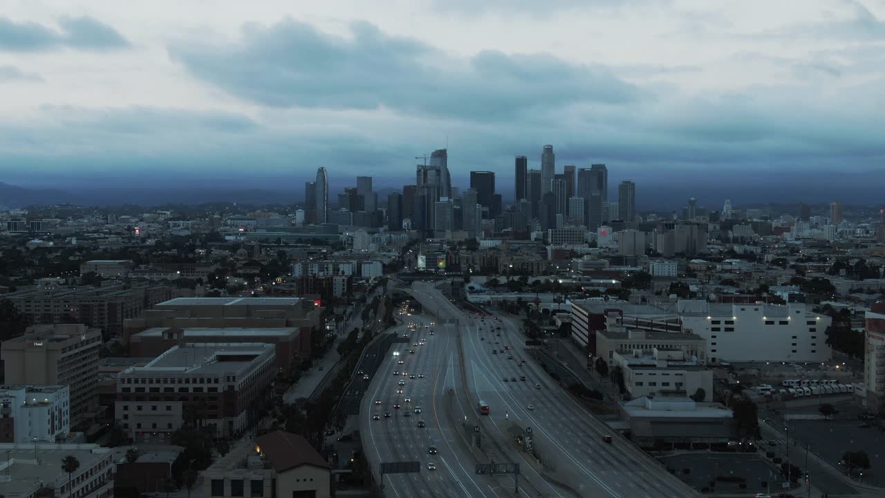 空中拍摄的交通在市中心的高速公路对天空，无人机向后飞行在城市景观在黄昏-洛杉矶，加利福尼亚视频素材