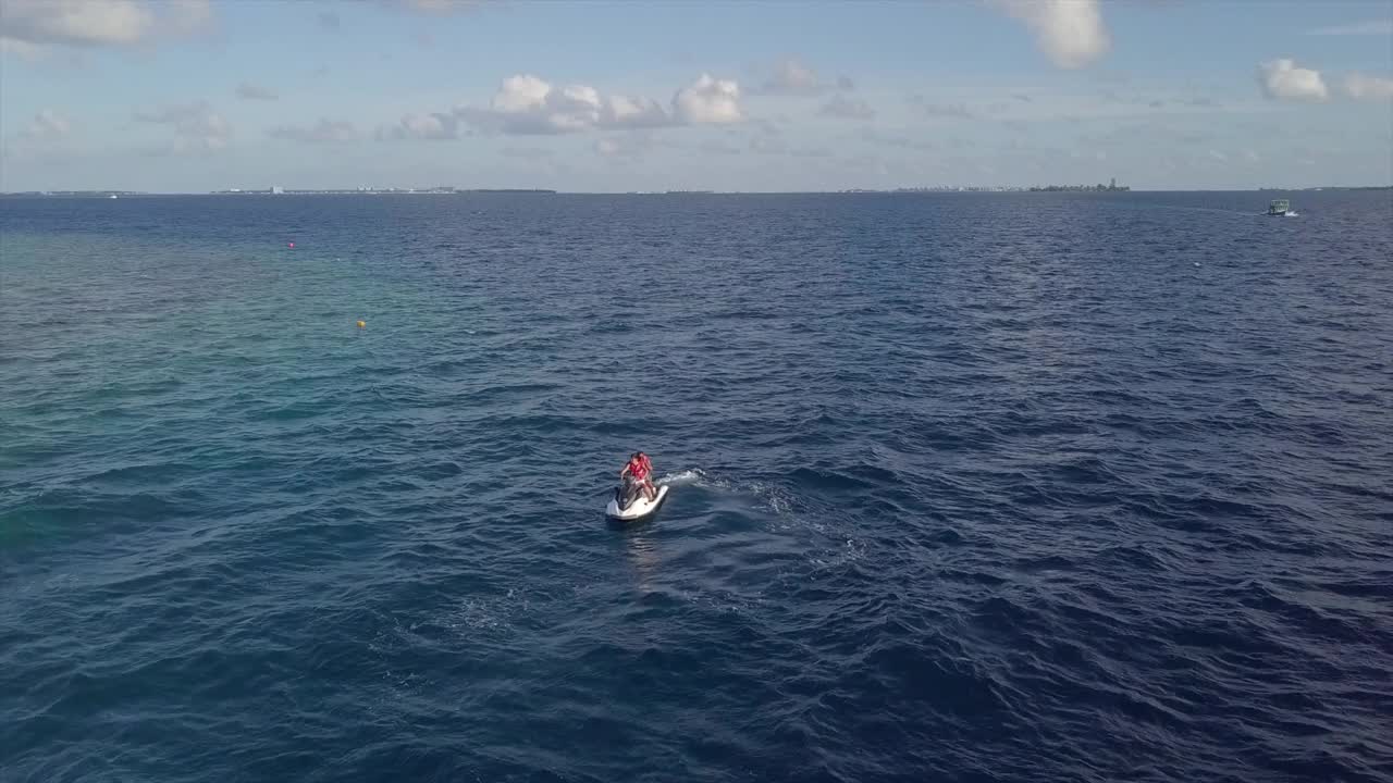 空中摇摄人们在绿松石海上滑雪对天空，无人机飞行附近的游客享受水上运动-南马列环礁，马尔代夫视频素材