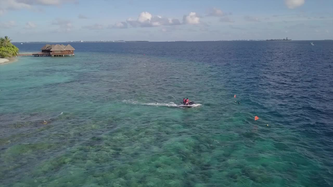 空中摇摄游客在绿松石海上滑雪对天空，无人机飞行附近的人享受水上运动-南马莱环礁，马尔代夫视频素材