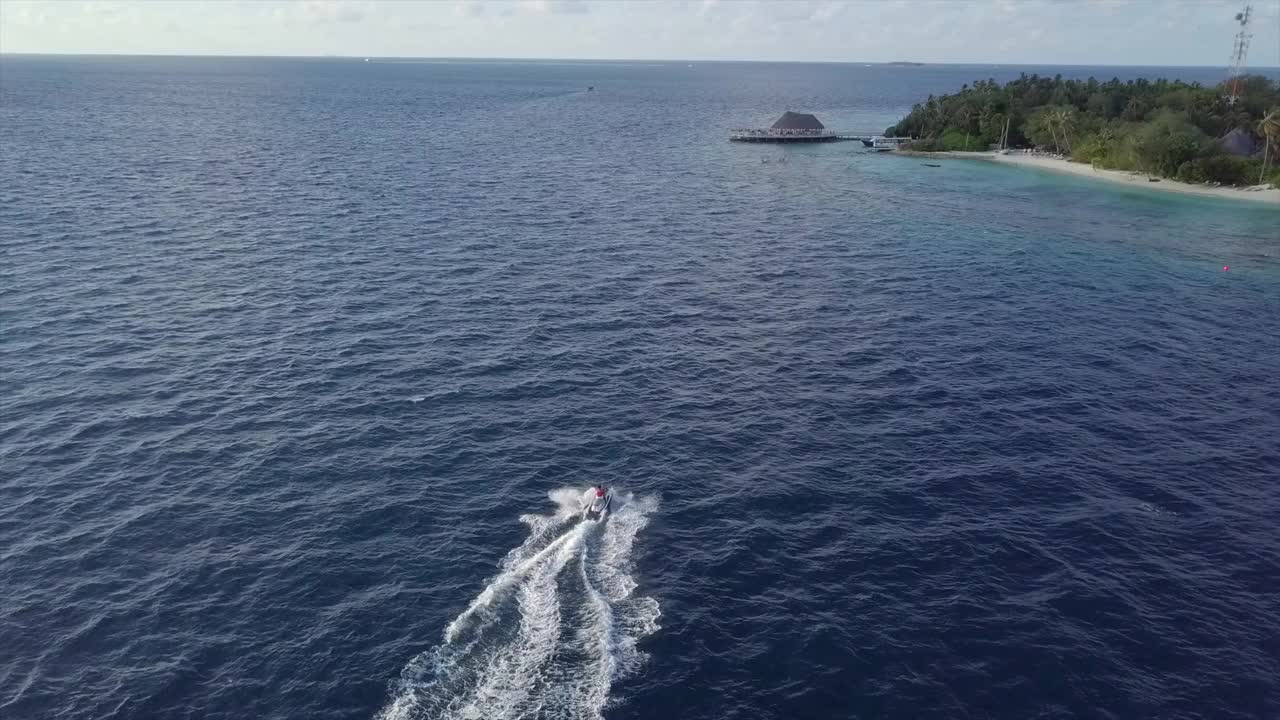 空中拍摄的人在水上摩托艇在阳光明媚的一天，无人机向前飞在游客溅水对天空-南马累环礁，马尔代夫视频素材