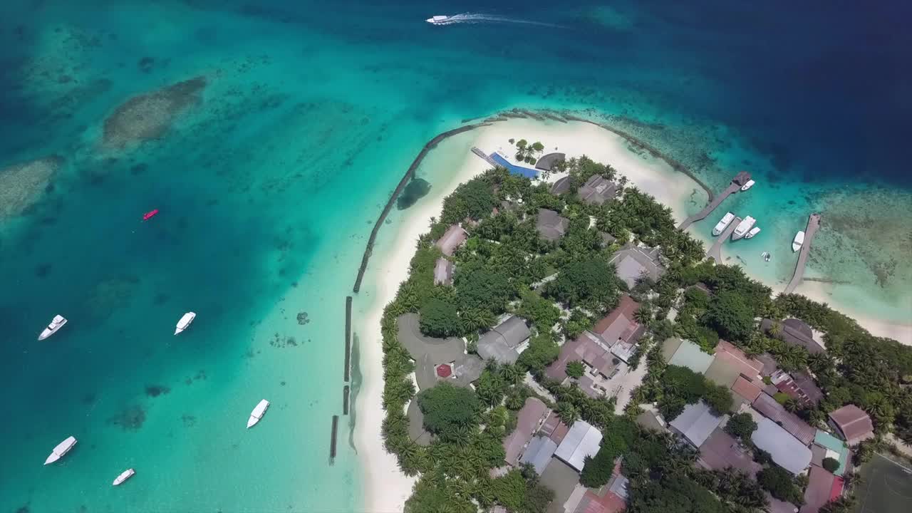 航拍豪华度假村在绿松石海上的船，无人机向前飞行在海滩酒店在阳光灿烂的一天-南马列环礁，马尔代夫视频素材