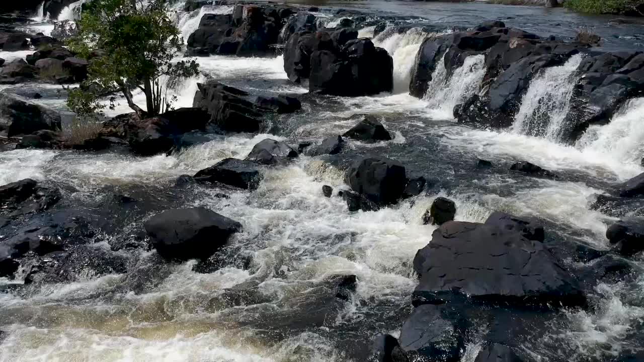 近距离观察小急流和流经黑色岩石的水流视频素材