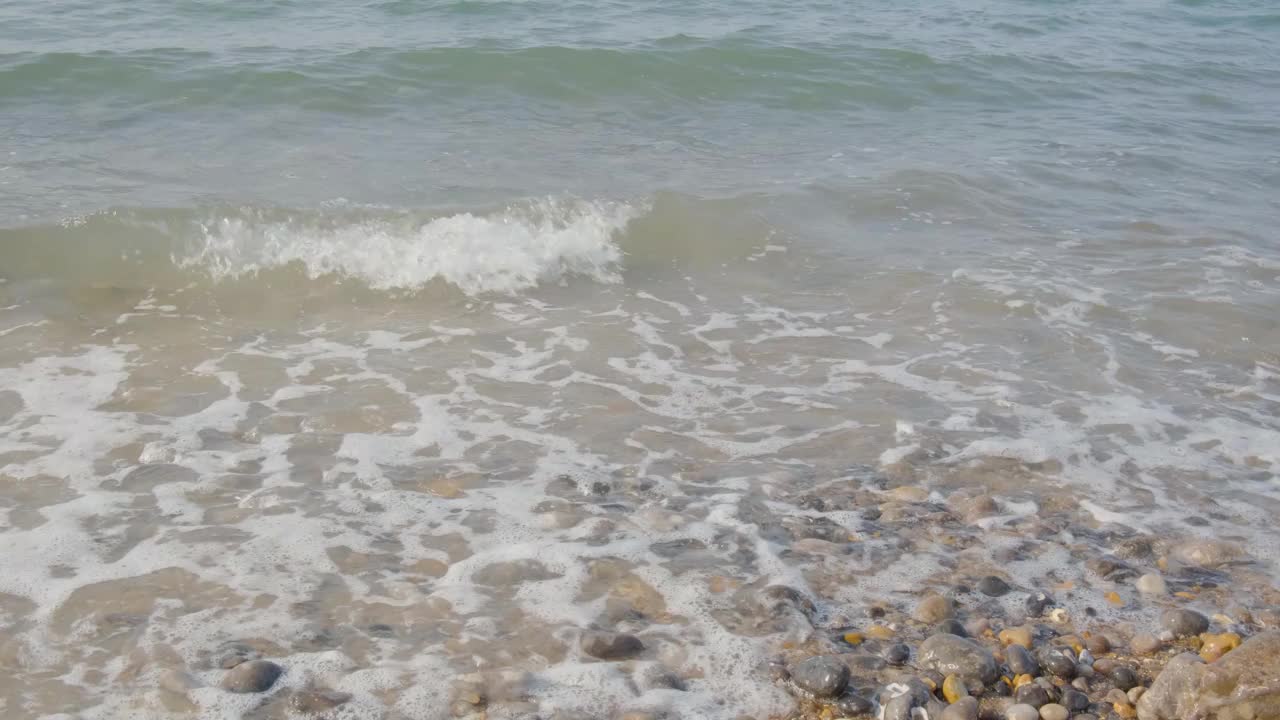 海水拍打着岸边的圆卵石，强大的海浪沉思的奇观，从上面看视频下载