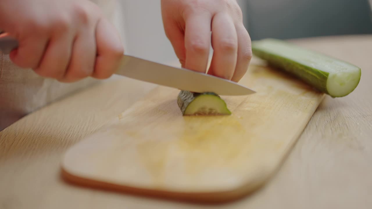 女人把新鲜的黄瓜切在桌子上，准备饭菜，食谱配料视频素材