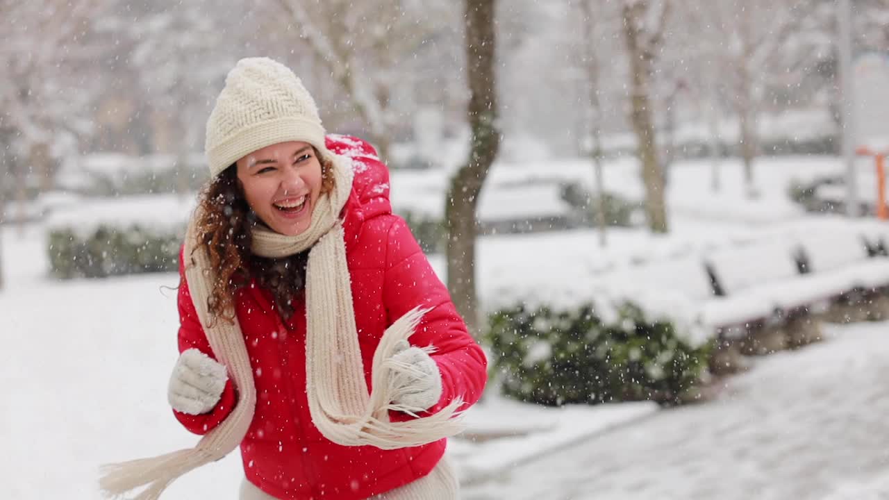 一个快乐的年轻女子在白雪覆盖的公园里玩雪球视频素材