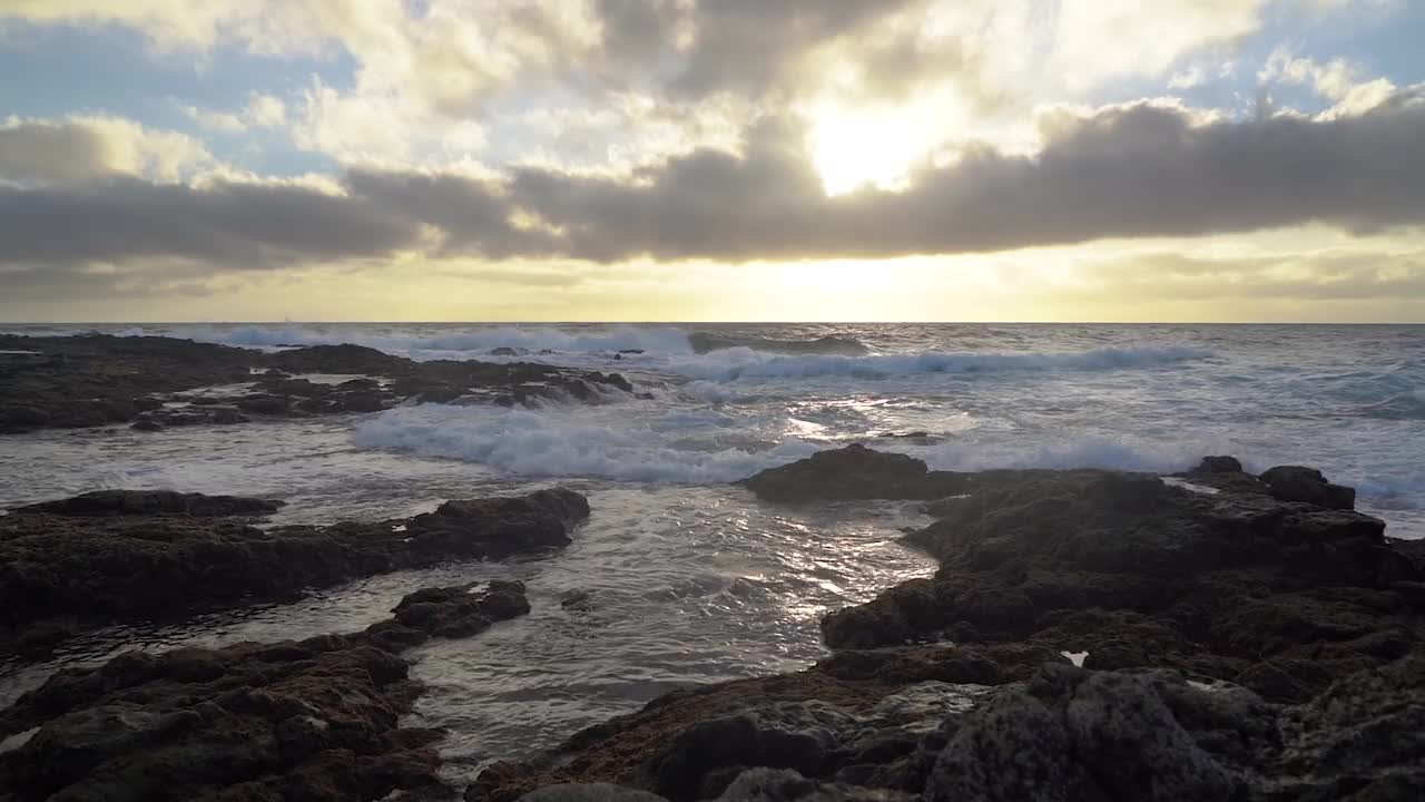 日落的海景与海浪撞击岩石和日落在地平线上。视频素材