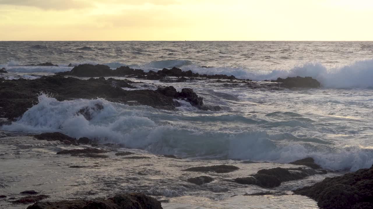 日落的海景与海浪撞击岩石和日落在地平线上。视频素材