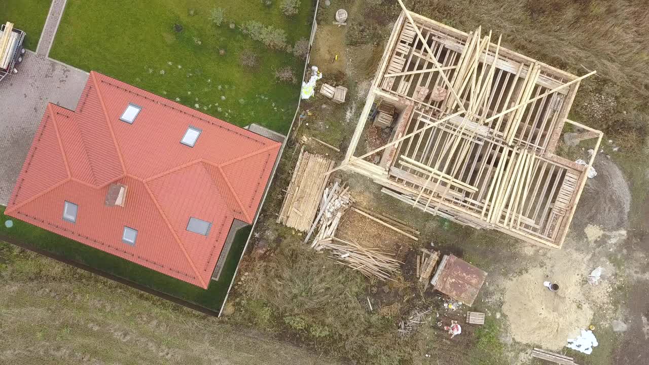 两个私人住宅的上下鸟瞰图，其中一个是木质的屋顶框架，另一个是红瓦的屋顶。视频素材