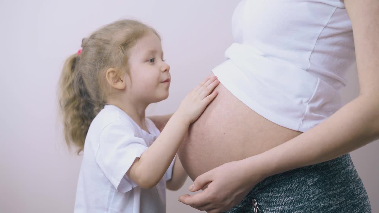 可爱的孩子抱着大肚子跟孕妇说话视频素材