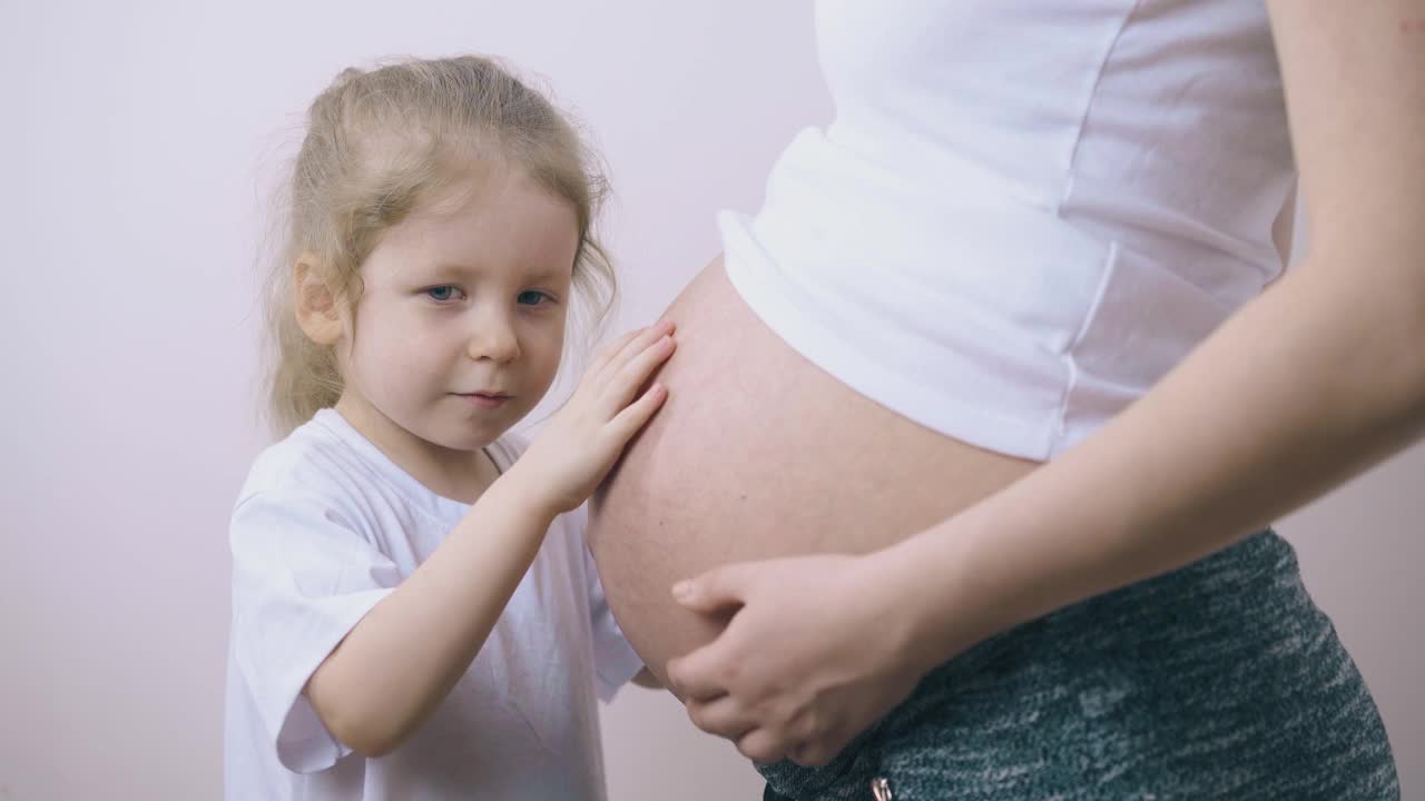 女孩跟怀孕的妈妈说让宝宝摸肚子视频素材