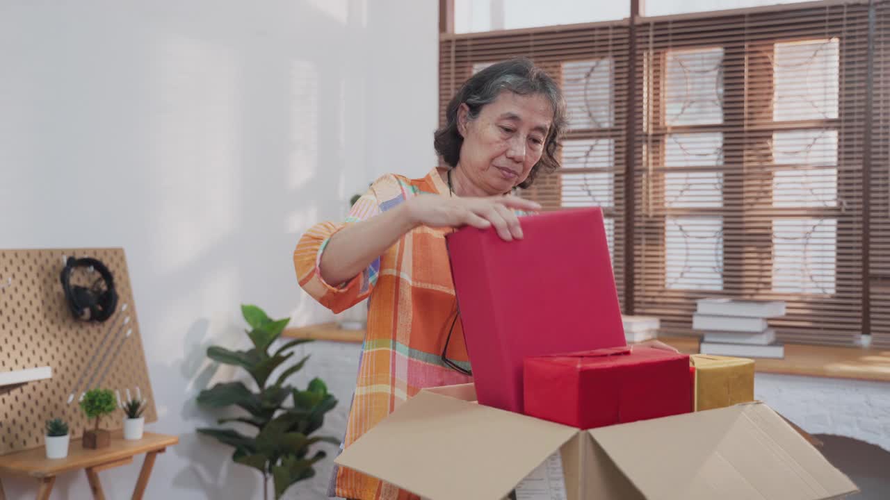 亚洲高级妇女打开纸板箱从网上购物和检查商品里面视频素材