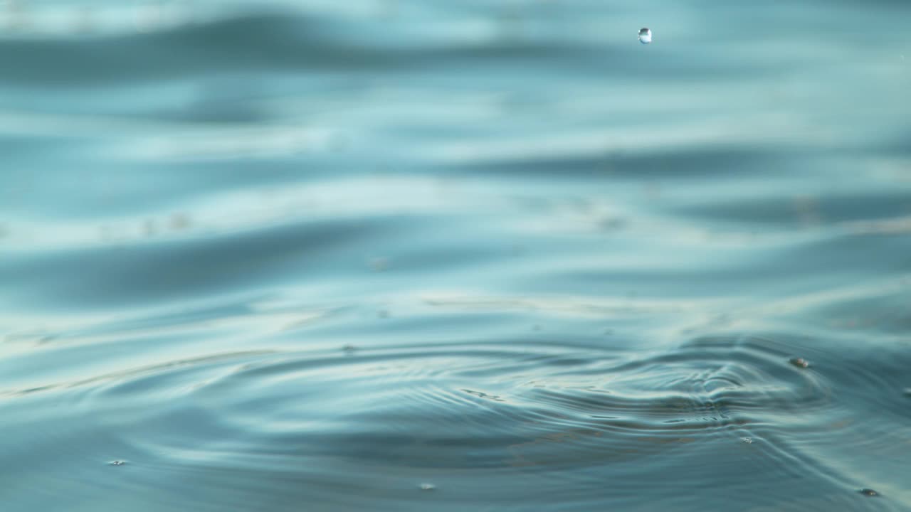 特写:微小的水滴在平静的海面上产生涟漪的电影镜头视频素材