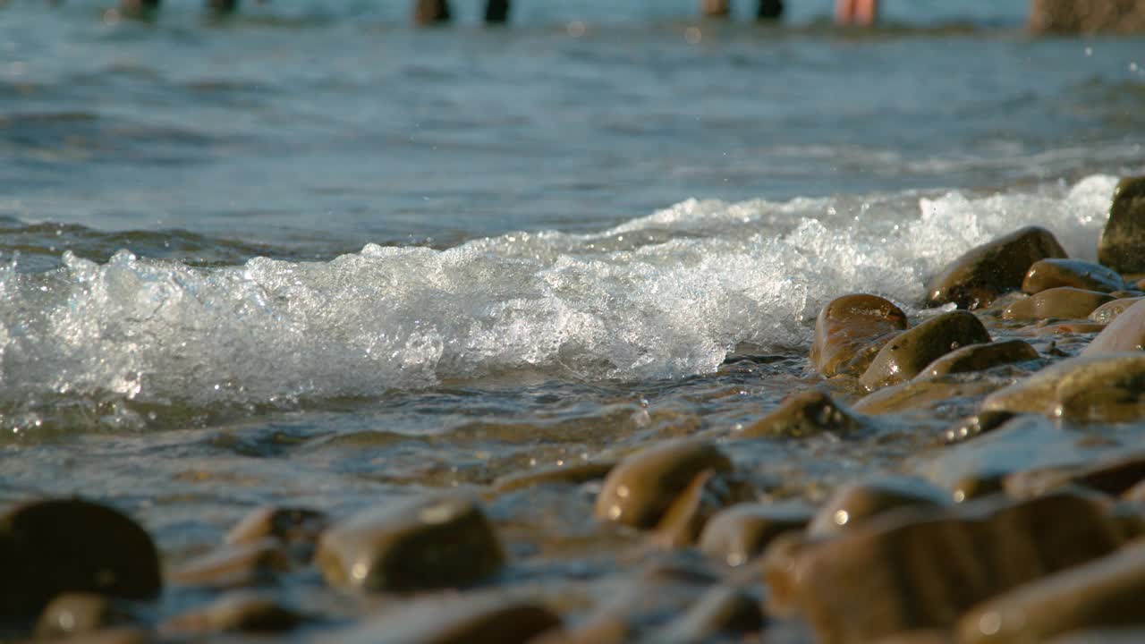 近距离观察:泡沫状的海浪扫过棕色卵石滩。视频素材