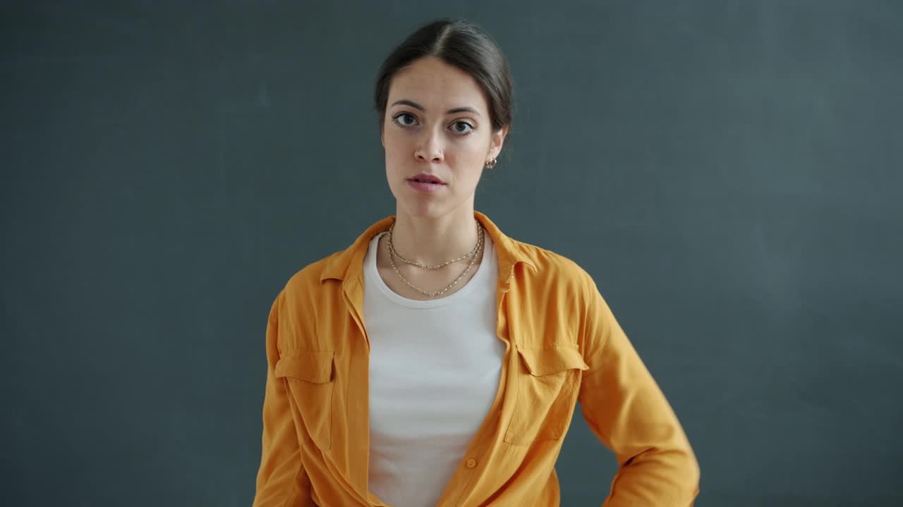 女学生的肖像，在头部扭手指做傻瓜标志看着相机视频素材