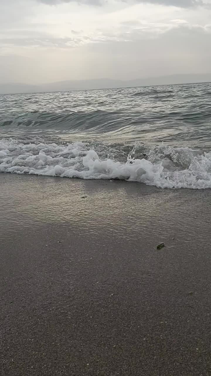 在多云的地平线上，海浪拍打着海滩视频下载