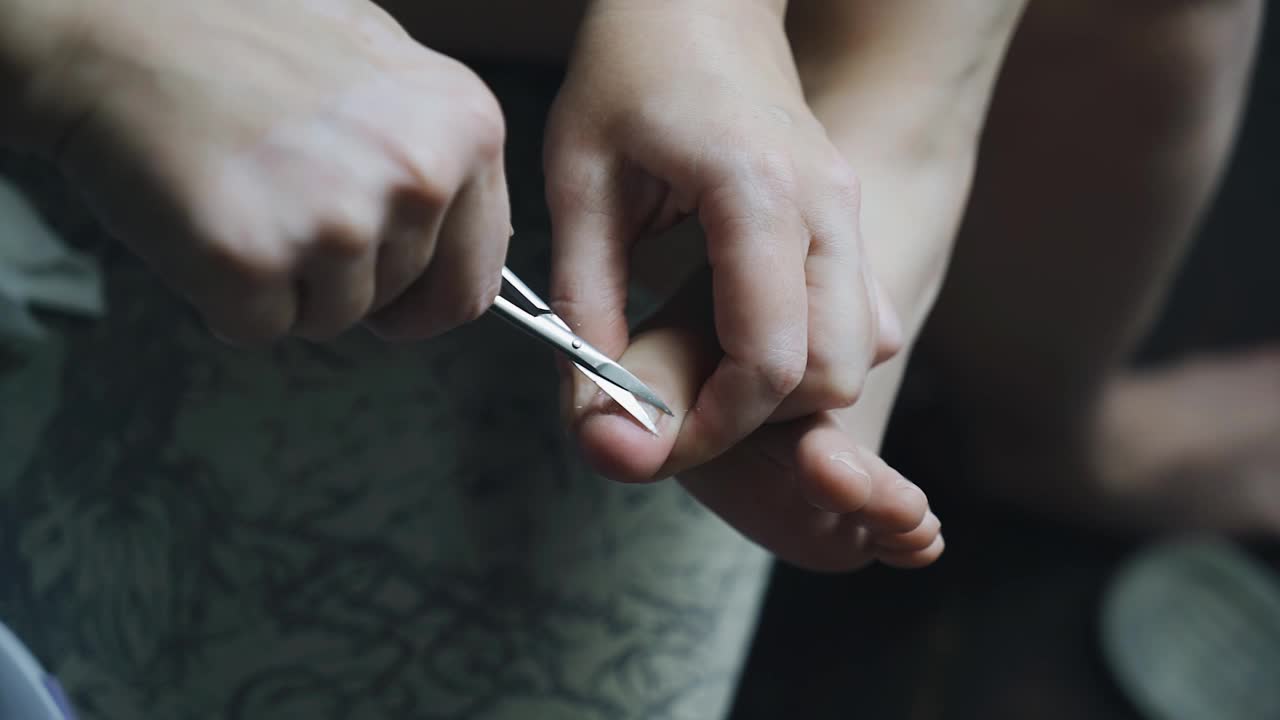 这个女孩用剪刀剪脚趾甲。近距离射击视频素材