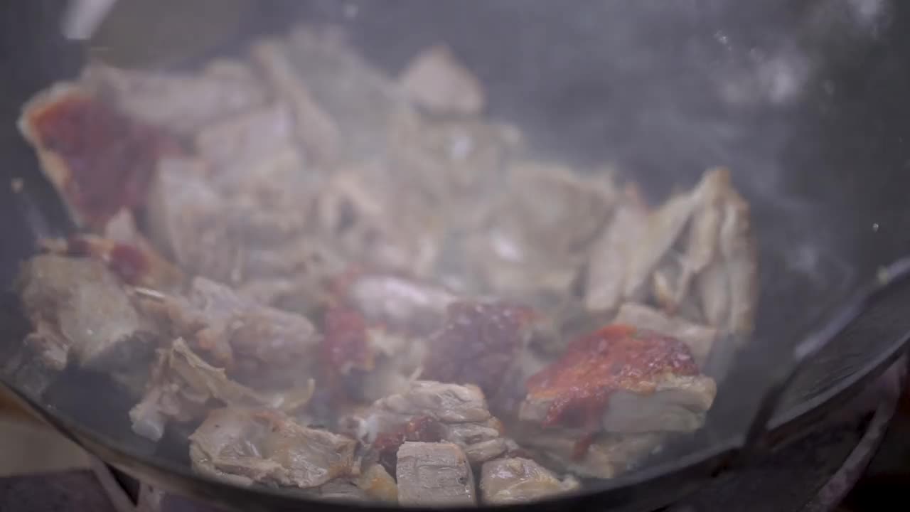 用炉子上的油锅炒鸭肉，用热油炒鸭肉，特写镜头视频素材