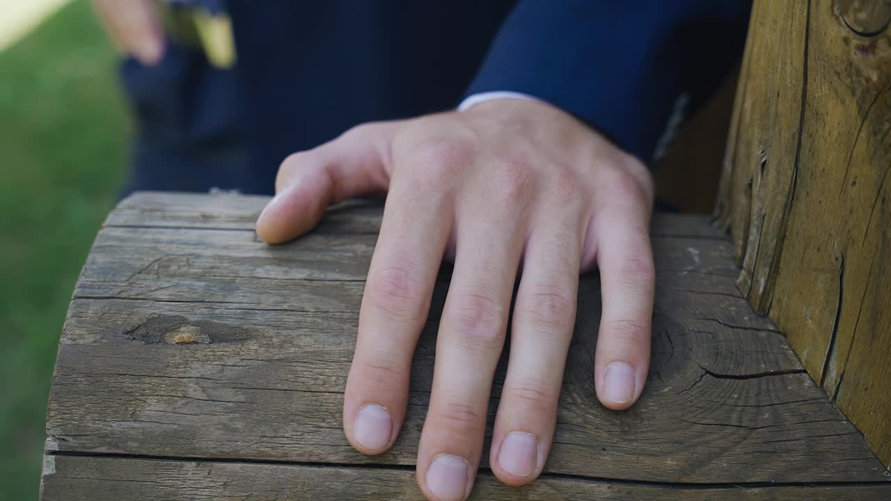 一个男人拉着他的手站在房子边缘的一根木头上。手的特写镜头视频素材