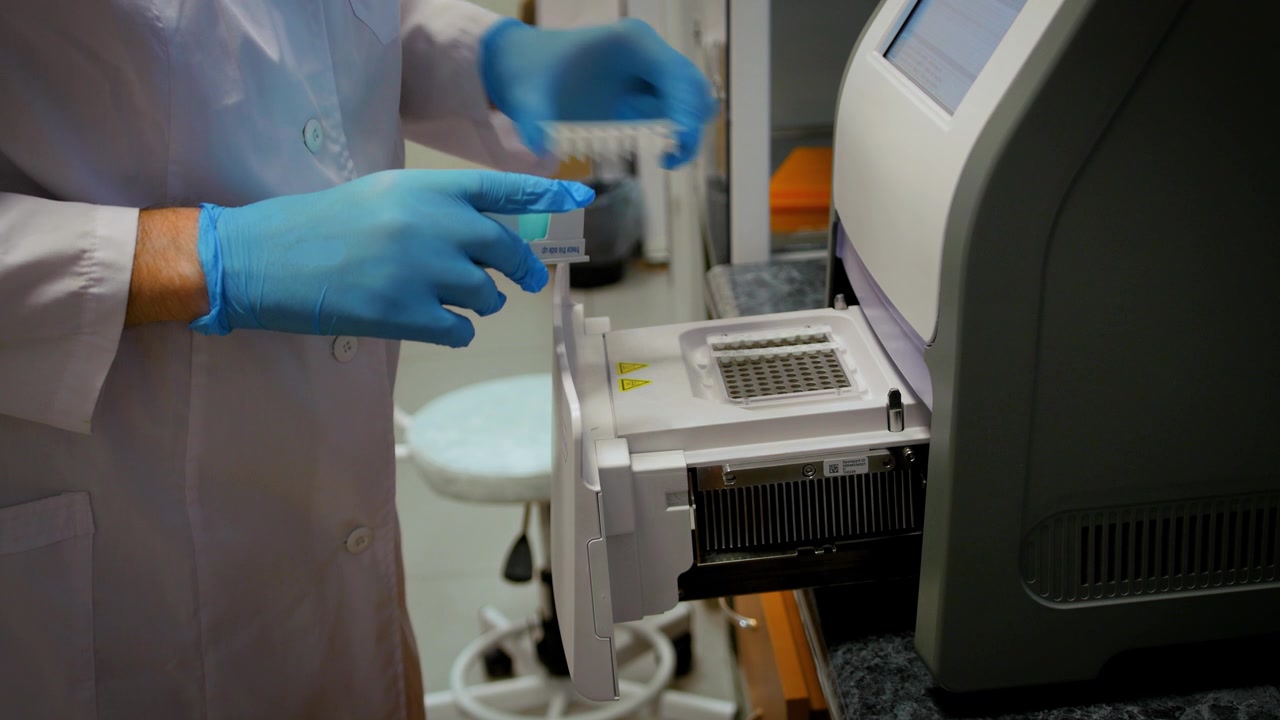 戴手套、穿白大褂的医生或科学家将装有试验品的试管装入仪器视频素材画面4