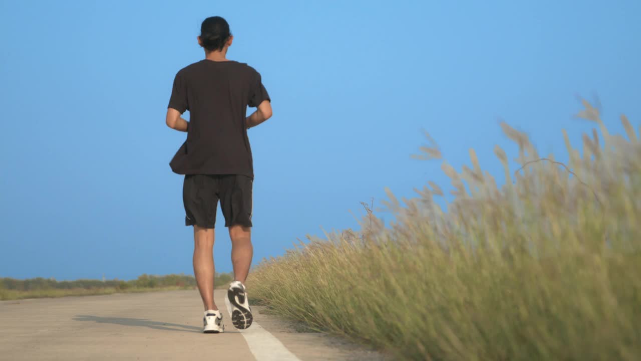 亚洲人在公路上奔跑。适合男性健身跑步者在户外锻炼和锻炼视频下载