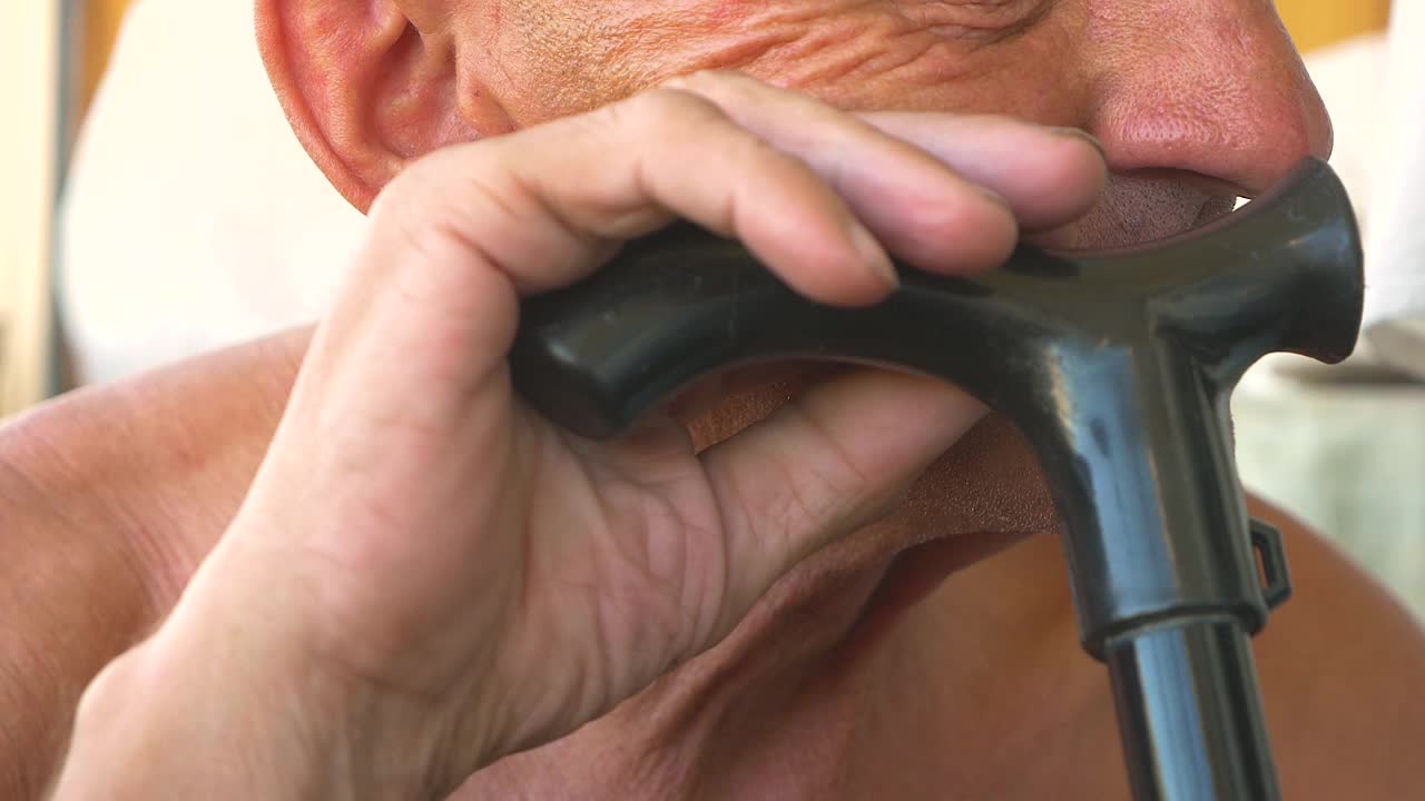 那个白种老人疲惫地低头靠着手杖。一位70多岁的老人坐在那里，手里拿着一根手杖。孤独的男人悲伤的主题选择焦点视频素材