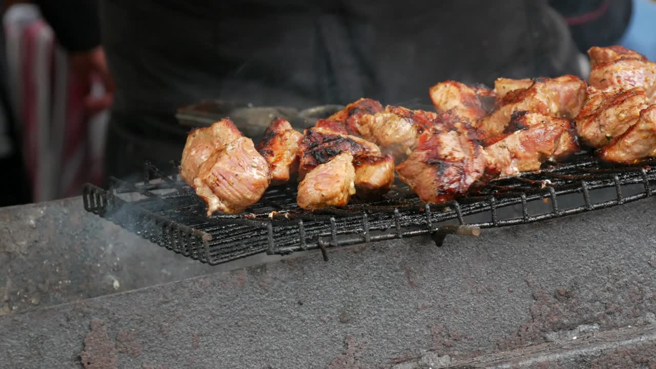 烧烤盘的特写镜头。用特制的钳子把肉翻面。美味的食物在金属烤肉串。野餐时间到了。街头食品。美食节。赌注下的猪肉。炒猪肉。视频素材