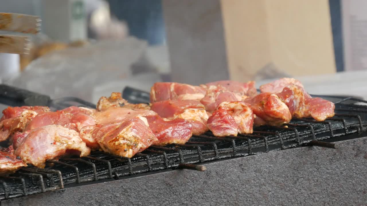 烧烤盘的特写镜头。用特制的钳子把肉翻面。美味的食物在金属烤肉串。野餐时间到了。街头食品。美食节。赌注下的猪肉。炒猪肉。视频素材