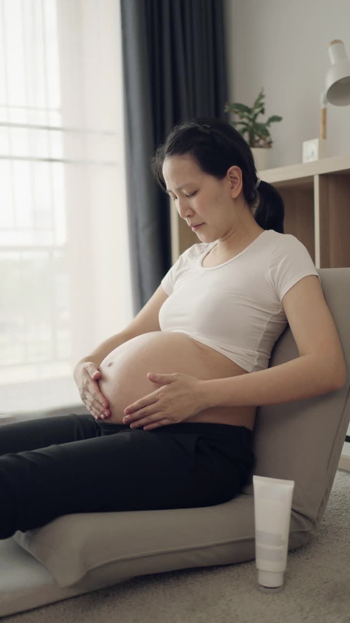 孕妇在家里把润肤霜涂在腹部视频素材