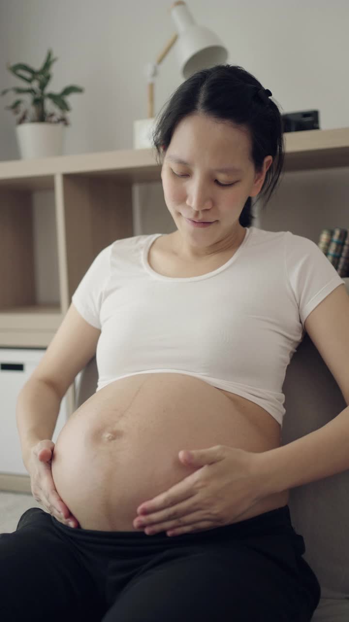 孕妇在家里把润肤霜涂在腹部视频素材