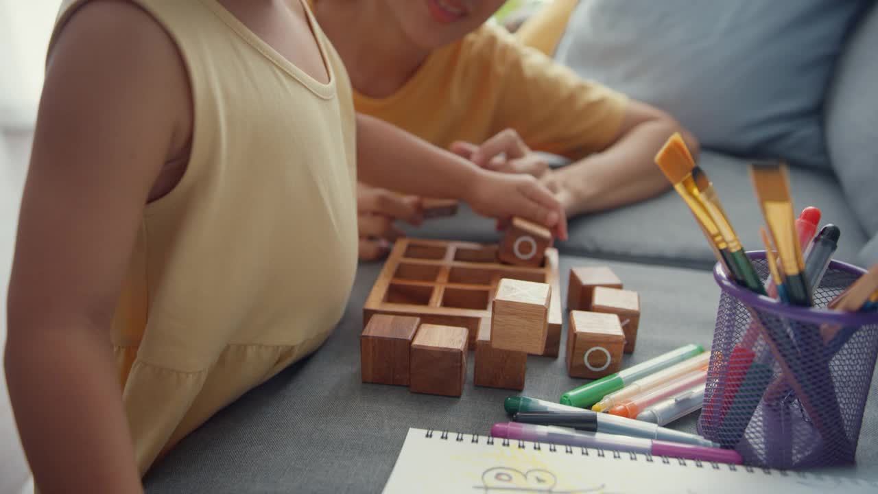 快乐开朗的亚洲家庭妈妈教女孩玩棋盘游戏的爱好，在家里的客厅沙发上放松。视频素材