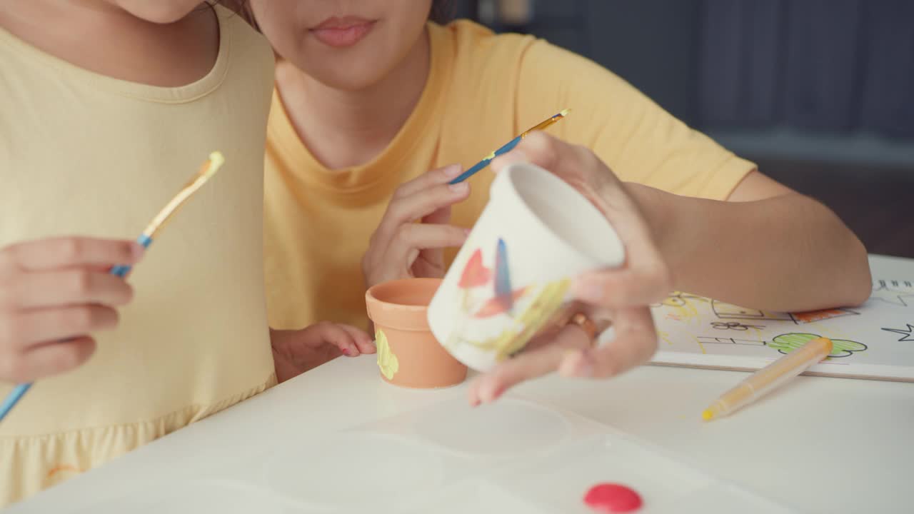 快乐快乐的亚洲家庭妈妈教学步的小女孩在家里客厅的桌子上画画，玩得开心放松。视频素材